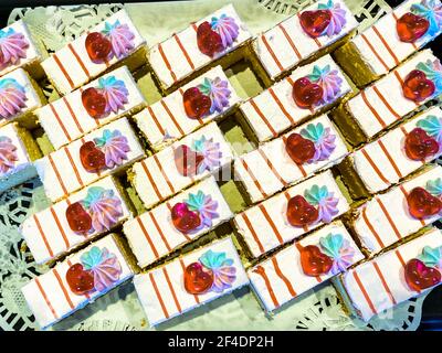 Köstliche verzierte Kuchen in Scheiben mit Schokolade und Sahne in einem Reihe hinter dem Schaufenster der Konditorei Stockfoto