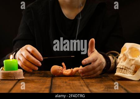 Ein Wahrsager, orakel oder Zauberin zaubert über eine Babypuppe. Psychische Lesungen und das Konzept der Hellsichtigkeit. Stockfoto