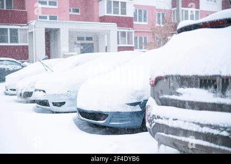 Ein paar Autos unter Schnee im Winter bedeckt, stürmisches Wetter draußen Stockfoto