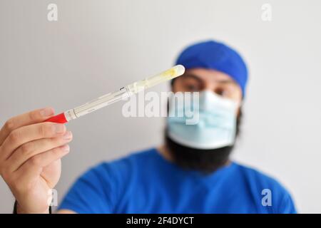 Krankenschwester hält einen Schlauch. Rotavirus-Test. Mann trägt eine Gesichtsmaske greifen eine Probe von Kot in einem Labor untersucht Stockfoto