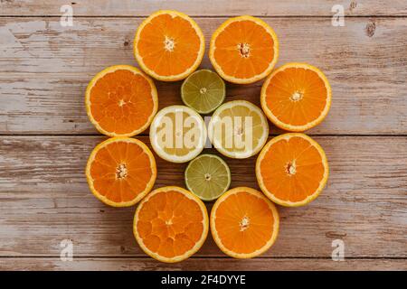 Orangen, Limetten und Zitronen gleiten auf Holztisch Ansicht von oben. Schöner Hintergrund mit frischem Obst halb geschnitten.gesunde Ernährung Vitamin C.Sommer tropic Stockfoto