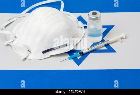 Israel Flagge, N95 Gesichtsmaske, Nadelspritze und Fläschchen. Konzept der Covid-19 Coronavirus-Impfstoffverteilung, Versorgungsengpässe und Gesundheitskrise Stockfoto