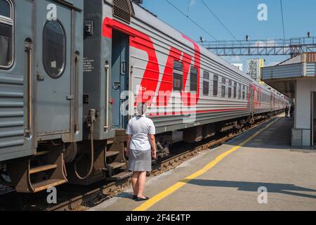 Ein Waggonwart der Provodnitsa am Bahnhof Nowosibirsk-Glavny in Nowosibirsk, Russland, ein wichtiger Halt entlang der Transsibirischen Eisenbahn. Stockfoto