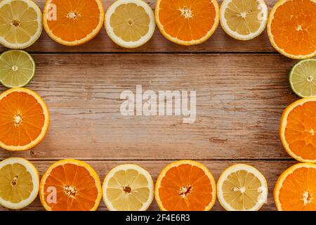 Orangen, Limetten und Zitronen Rutschen auf Holztisch Blick von oben. Wunderschön Hintergrund mit frischem Obst halb geschnitten.gesunde Ernährung Vitamin C.Sommer tropica Stockfoto