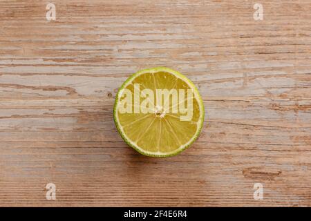 Blick von oben auf frisch geerntete Früchte. Süße, saftige, halbgeschnittene Limette auf dem Holztisch. Gesunde Ernährung Vitamin C.Sommer tropische Früchte Food Konzept flach legen. Stockfoto