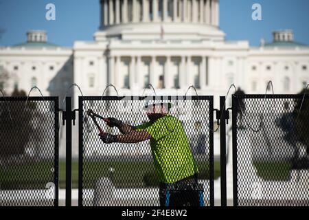 Washington, USA. März 2021, 20th. Ein Arbeiter entfernt am Samstag, den 20. März, Rasierdraht aus dem temporären Sicherheitszaun um das US-Kapitol in Washington, DC, 2021. Mehr als 10 Wochen nach dem Pro-Trump-Aufstand im Januar 6th begann der vorübergehende Sicherheitszaun um den Capitol-Komplex herabzufallen. (Graeme Sloan/Sipa USA) Quelle: SIPA USA/Alamy Live News Stockfoto