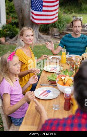 Kaukasischer Mann, der Gnade mit der Familie sagt, bevor er zusammen isst Im Garten Stockfoto