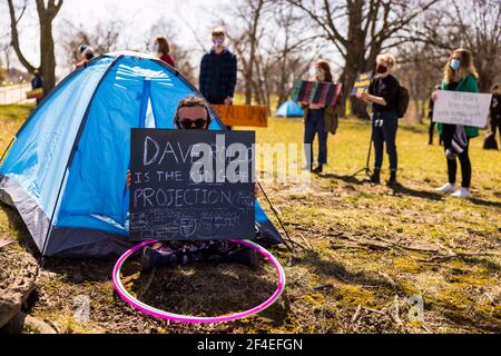 Ein Protestler sitzt in einem Zelt, das als Teil eines Protestes in den Reitfeldern nahe Memorial Stadium aufgestellt wird. Eine Koalition von Mitgliedern der Bloomington-Gemeinschaft, Aktivisten, Und Indiana University Studenten marschieren von Dunn Meadow zu Simon Skjodt Assembly Hall während der "March to End the Madness", um gegen die City of Bloomington Behandlung von unbewohnten Bewohnern Pitching Zelte auf öffentlichem Eigentum und die 10 Millionen Dollar Abfindungszahlung Indiana University muss gefeuert zu zahlen Basketballtrainer Archie Miller für Herren. Mehrere Spiele für die NCAA Basketball-Turnier wurden innerhalb von Assembl gespielt Stockfoto