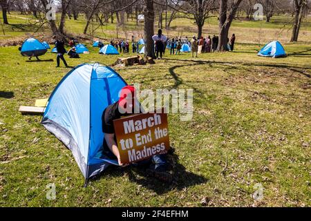 Ein Protestler sitzt in einem Zelt, das als Teil eines Protestes in den Reitfeldern nahe Memorial Stadium aufgestellt wird. Eine Koalition von Mitgliedern der Bloomington-Gemeinschaft, Aktivisten, Und Indiana University Studenten marschieren von Dunn Meadow zu Simon Skjodt Assembly Hall während der "March to End the Madness", um gegen die City of Bloomington Behandlung von unbewohnten Bewohnern Pitching Zelte auf öffentlichem Eigentum und die 10 Millionen Dollar Abfindungszahlung Indiana University muss gefeuert zu zahlen Basketballtrainer Archie Miller für Herren. Mehrere Spiele für die NCAA Basketball-Turnier wurden innerhalb von Assembl gespielt Stockfoto
