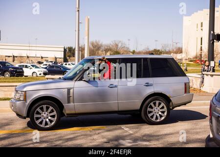 Vorbeifahrende NCAA-Basketballfans, die die Assembly Hall verlassen, machen Solidaritätsfäuste zur Unterstützung der Demonstranten. Eine Koalition von Mitgliedern der Bloomington-Gemeinschaft, Aktivisten, Und Indiana University Studenten marschieren von Dunn Meadow zu Simon Skjodt Assembly Hall während der "March to End the Madness", um gegen die City of Bloomington Behandlung von unbewohnten Bewohnern Pitching Zelte auf öffentlichem Eigentum und die 10 Millionen Dollar Abfindungszahlung Indiana University muss gefeuert zu zahlen Basketballtrainer Archie Miller für Herren. Mehrere Spiele für die NCAA Basketball-Turnier wurden innerhalb von Assembly Hal gespielt Stockfoto