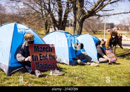 Die Demonstranten sitzen in Zelten, die als Teil eines Protestes auf den Reitfeldern in der Nähe des Memorial Stadions aufgestellt wurden. Eine Koalition von Mitgliedern der Bloomington-Gemeinschaft, Aktivisten, Und Indiana University Studenten marschieren von Dunn Meadow zu Simon Skjodt Assembly Hall während der "March to End the Madness", um gegen die City of Bloomington Behandlung von unbewohnten Bewohnern Pitching Zelte auf öffentlichem Eigentum und die 10 Millionen Dollar Abfindungszahlung Indiana University muss gefeuert zu zahlen Basketballtrainer Archie Miller für Herren. Mehrere Spiele für die NCAA Basketball-Turnier wurden innerhalb der Assembly H gespielt Stockfoto