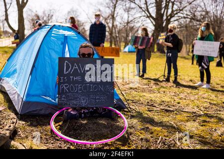 Ein Protestler sitzt in einem Zelt, das als Teil eines Protestes in den Reitfeldern nahe Memorial Stadium aufgestellt wird. Eine Koalition von Mitgliedern der Bloomington-Gemeinschaft, Aktivisten, Und Indiana University Studenten marschieren von Dunn Meadow zu Simon Skjodt Assembly Hall während der "March to End the Madness", um gegen die City of Bloomington Behandlung von unbewohnten Bewohnern Pitching Zelte auf öffentlichem Eigentum und die 10 Millionen Dollar Abfindungszahlung Indiana University muss gefeuert zu zahlen Basketballtrainer Archie Miller für Herren. Mehrere Spiele für die NCAA Basketball-Turnier wurden innerhalb von Assembl gespielt Stockfoto
