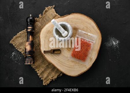 Holzquerschnitt mit Safran in Plastikverpackung und Stein Mörtel und Mühle Stockfoto