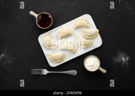 Tiefgefrorene Vareniki mit Heidelbeere auf Marmorplatte Stockfoto