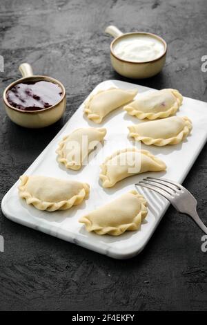 Tiefgefrorene Vareniki mit Heidelbeere auf Marmorplatte Stockfoto