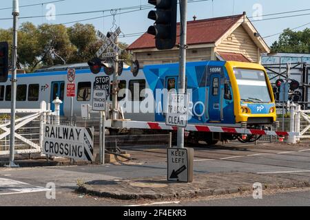 Ein Zug, der durch einen Bahnübergang in Clifton Hill, Melbourne, Victoria, Australien fährt Stockfoto