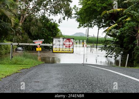 Ein Warnzeichen, dass die Brücke unter Wasser steht und Überschwemmungen die Straße im tropischen Norden Queenslands, Australien, aufgrund von starken Regenfällen gesperrt haben. Stockfoto