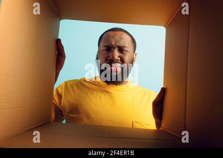 Der Mensch hat Zweifel und er ist angewidert über das, was in einem Paket ist. Konzept der Online-Shop Betrug Stockfoto