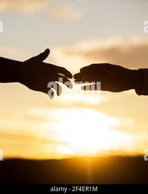 Rettung, helfende Geste oder Hände. Zwei Hände Silhouette auf Himmel Hintergrund, Verbindung oder Hilfe-Konzept. Ausgestreckte Hände, Rettung, helfen Silhouette Stockfoto