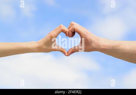 Hände in Form von Liebe Herz. Herz aus den Händen auf dem Hintergrund des Himmels. Liebe, Freundschaft Konzept. Mädchen und männliche Hand im Herzen bilden Liebe blauen Himmel. Weiblich Stockfoto