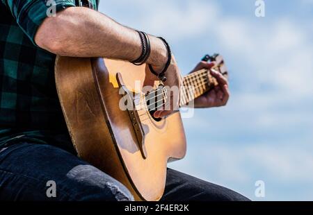 Die Hände des Mannes spielen akustische Gitarre, Nahaufnahme. Akustische Gitarren spielen. Musikkonzept. Gitarren akustisch. Männlicher Musiker, der Gitarre spielt, Musik Stockfoto