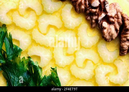 Geschnittener Sellerie mit Walnüssen und Petersilie diagonal Schuss auf ein Gelber Hintergrund Stockfoto