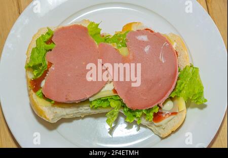 Bologna-Sandwich mit Salat, Brot, Mayonnaise und Ketchup. Natürliche und alternative Lebensmittel. Das Sandwich ist einer der bekanntesten und vielseitigsten Snacks Stockfoto