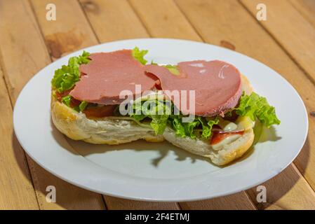 Bologna-Sandwich mit Salat, Brot, Mayonnaise und Ketchup. Natürliche und alternative Lebensmittel. Das Sandwich ist einer der bekanntesten und vielseitigsten Snacks Stockfoto