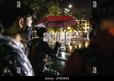 Während einer regierungsfeindlichen Demonstration in Bangkok hält ein prodemokratischer Protestler einen Regenschirm in der Hand, während er vor Polizeibeamten steht. Tausende von prodemokratischen Demonstranten versammelten sich in der Nähe des Großen Palastes in Sanam Luang und forderten den Rücktritt des thailändischen Premierministers und die Reform der Monarchie. Die Demonstranten verurteilten auch die Anwendung des Gesetzes von Lese majeste gemäß Abschnitt 112 des Strafgesetzbuches. Der von REDEM (Restart Democracy) organisierte Protest endete mit mehreren Zusammenstößen, dem Einsatz von Wasserwerfern, Tränengas und Gummigeschossen, die mehrere Verletzte hinterließen. Stockfoto