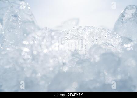 Transparente, leuchtende Eiszapfen aus der Nähe glitzern an gefrorenen wilden Seeufern bei Sonnenuntergang. Kalter Winter Natur Hintergrund Stockfoto