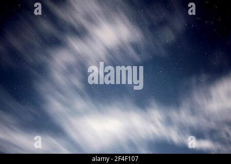 Verschwommene Wolken schweben am Abend mit Sternen am Himmel. Langzeitbelichtung verwendet. Stockfoto