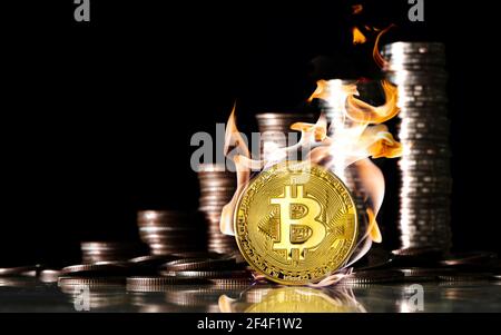 Bitcoin im Feuer auf dem Hintergrund der Münzen von Baht. Finanz- und Investitionskonzept. Stockfoto