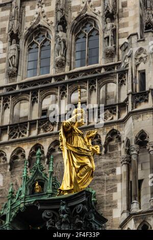 Statue der Jungfrau Maria am Marienplatz, München, Deutschland. Dieses Hotel ist ein Wahrzeichen Münchens. Goldene Skulptur auf Mariensaule-Säule auf Rückenfigur Stockfoto