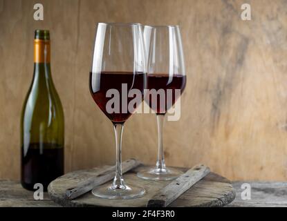 Zwei Gläser Rotwein. Die Flasche Wein steht auf dem Tisch. Weinhintergrund. Stillleben. Alkoholisches Getränk in einem Glas. Holzhintergrund Stockfoto