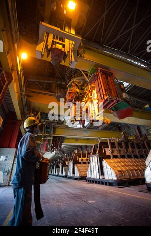 Aluminiumelektrolyseanlage. Schlackenhandling Kran und Elektrolyse Bäder. Fahrer in gelbem Helm und Fernbedienung Stockfoto