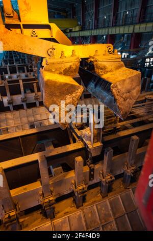 Aluminiumelektrolyseanlage. Kraneimer für Schlackenhandhabung. Elektrolysebad auf dem Hintergrund. Stockfoto