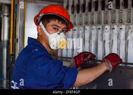 Taldykorgan, Kasachstan - Juni 06 2012: Akkumulator-Recycling-Anlage Kainar. Junge asiatische Arbeiter Betrieb Elektrolyse-Recycling-Maschine. Stockfoto