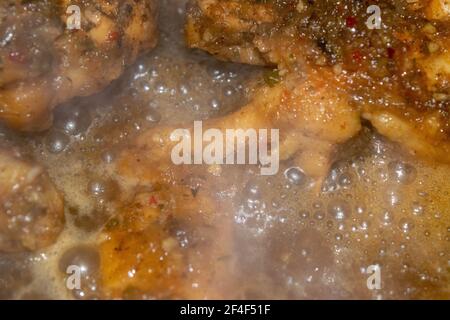 Kleine Stücke Hühnerfleisch werden mit Gewürzen geschmort. Nahaufnahme mit selektivem Fokus. Stockfoto