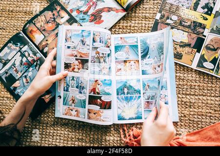 Frau liest Manga-Comic-Buch auf dem Teppich zu Hause. Stockfoto