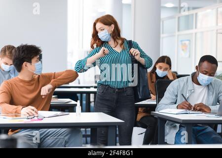 Verschiedene Menschen tragen Einweg-Gesichtsmasken Gruß und stoßen Ellbogen Stockfoto