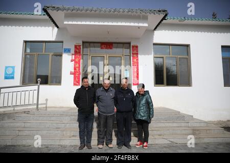 (210321) -- SUNAN, 21. März 2021 (Xinhua) -- Gu Zhengli (2nd L) posiert für ein Bild mit seinen Kollegen vor seiner Arbeitsstation in der Gemeinde Dahe, Yugu Autonomous County of Sunan, nordwestlich der Provinz Gansu, 20. März 2021. GU Zhengli, 59, arbeitet seit 42 Jahren an der Frontlinie des Wasserschutzprojekts Tanggaer in der Gemeinde Dahe, um die Sicherheit des Trinkwassers für die lokale Bevölkerung und Viehzucht zu gewährleisten. Da die jährliche Niederschlagsmenge in der Stadt nur 150 bis 300 Millimeter beträgt, ist das Wasserschutzprojekt Tanggaer buchstäblich die Lebensader für örtliche Hirten. Jeden Morgen Stockfoto