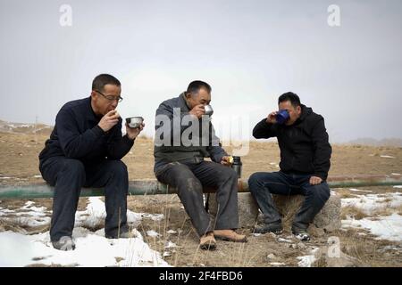 (210321) -- SUNAN, 21. März 2021 (Xinhua) -- Gu Zhengli (C) hat mit seinen Kollegen während einer Inspektionsreise in der Gemeinde Dahe, Yugu Autonomous County of Sunan, nordwestlich der Provinz Gansu, am 20. März 2021 zu Mittag gegessen. GU Zhengli, 59, arbeitet seit 42 Jahren an der Frontlinie des Wasserschutzprojekts Tanggaer in der Gemeinde Dahe, um die Sicherheit des Trinkwassers für die lokale Bevölkerung und Viehzucht zu gewährleisten. Da die jährliche Niederschlagsmenge in der Stadt nur 150 bis 300 Millimeter beträgt, ist das Wasserschutzprojekt Tanggaer buchstäblich die Lebensader für örtliche Hirten. Jeden Morgen steht Gu früh auf Stockfoto