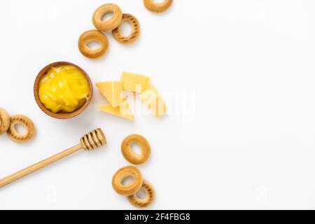 Honig in einer Holzschüssel, Bagels und Käse auf weißem Hintergrund Stockfoto