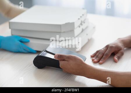 Millennial african american Kerl zahlen mit Smartphone mit leerem Bildschirm Am Terminal Stockfoto