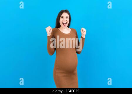 Junge schöne schwangere Frau auf isolierten farbigen Hintergrund feiert überrascht und erstaunt für den Erfolg mit den Armen angehoben und offenen Augen. Gewinner Konz Stockfoto