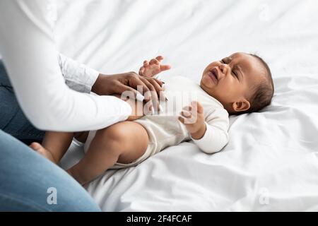 Schwarze Mutter tut Bauchmassage für weinende Säugling Stockfoto