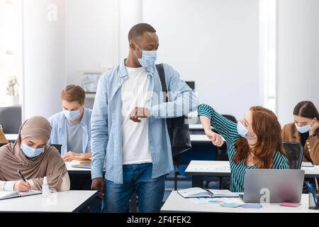 Verschiedene multikulturelle Menschen tragen Gesichtsmasken Begrüßung und stoßen Ellbogen Stockfoto