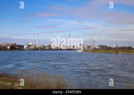 Krefeld (Uerdingen) - März 1. 2021: Blick über den Rhein auf das Industriegebiet mit Fabriken und Schornsteinen vor blauem Himmel Stockfoto