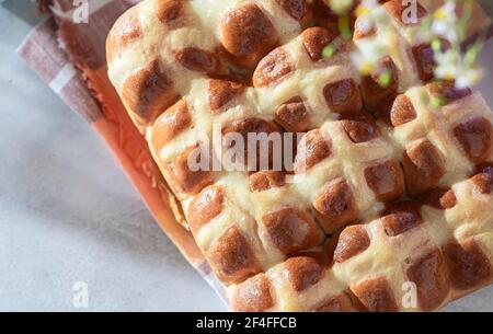 Hausgemachte Hot Cross Brötchen auf einem hellen Beton Hintergrund. Traditionelles Osteressen. Osterfeiertagskonzept. Britisches Essen Stockfoto