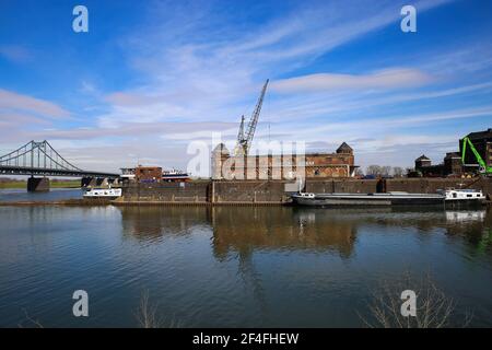 Krefeld (Ürdingen) - März 1. 2021: Blick auf alten Binnenladerhafen am Rhein mit Kran, Wasserschiff und Fabrikgebäude gegen Blue sk Stockfoto